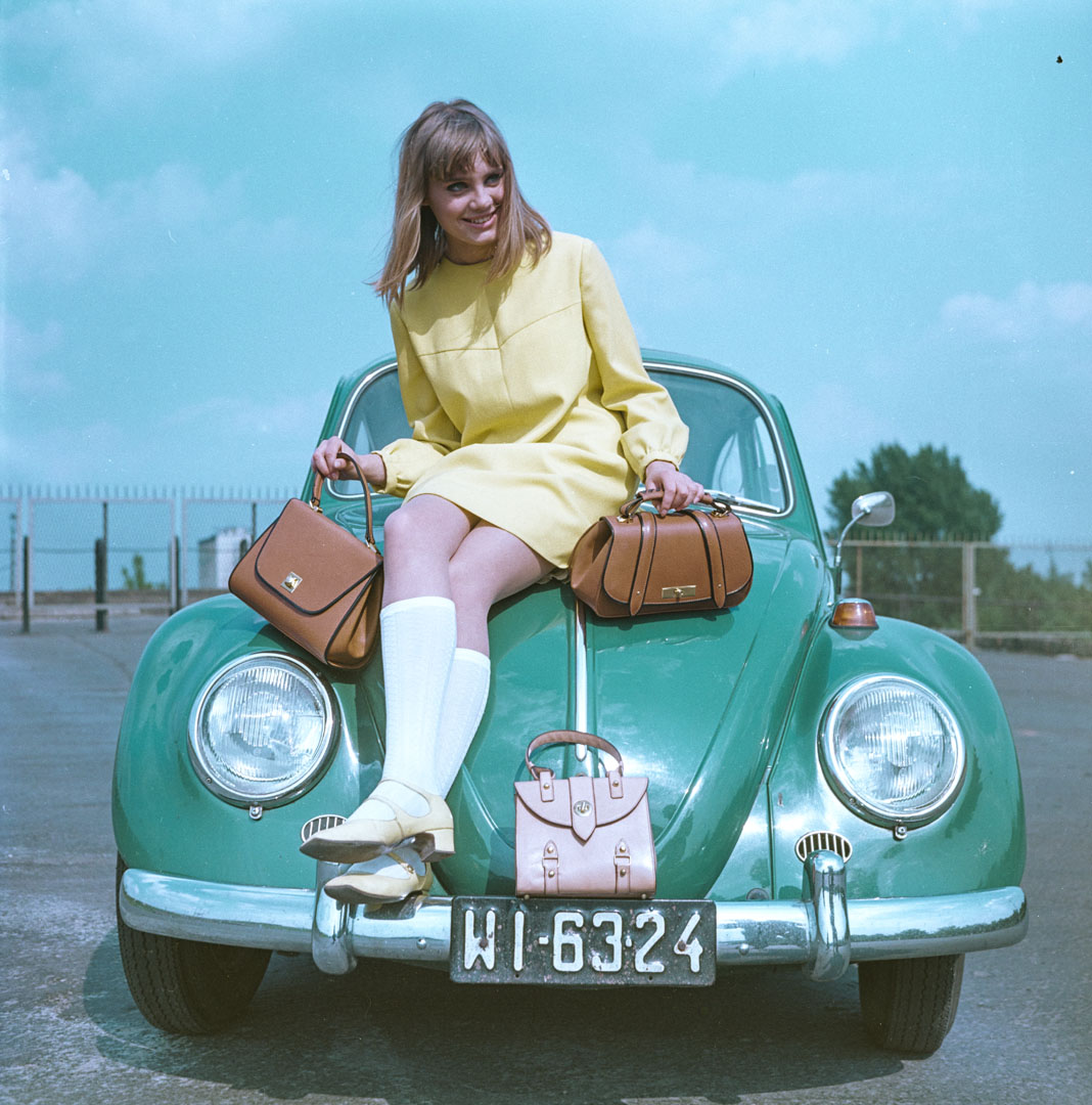 Kobieta w żółtej sukience siedząca na zielonym chrząszczu volkswagena.