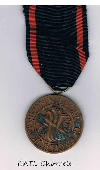 Medal z czerwono-czarną wstążką.