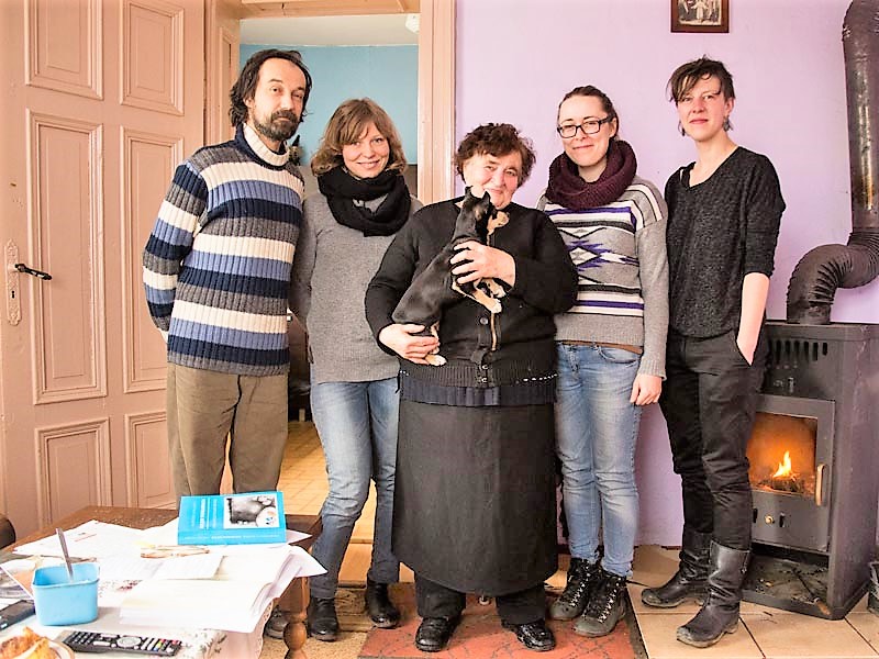 Grupa ludzi pozujących przed kominkiem.