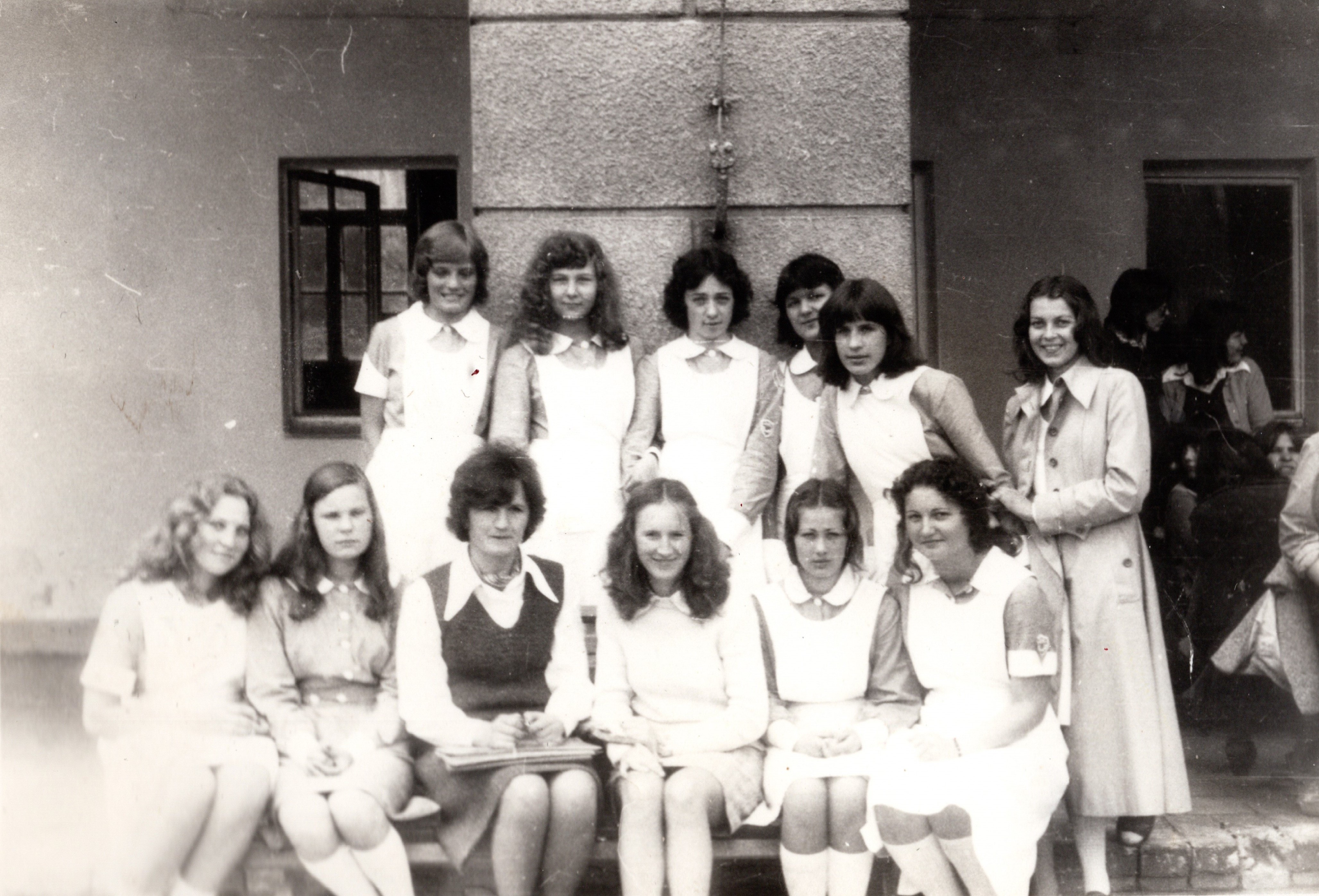 Grupa młodych kobiet w ubraniach vintage pozuje razem przed budynkiem.