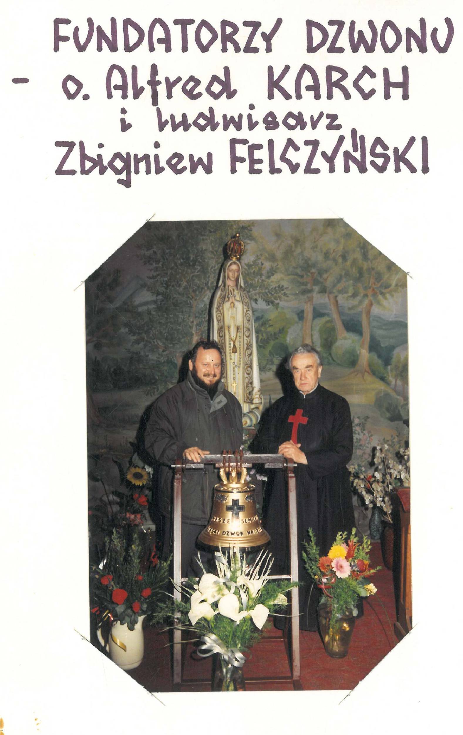 Dwóch mężczyzn stoi obok dzwonu i kwiatów przed posągiem. Tekst powyżej brzmi: „Fundatorzy dzwonu - o. Alfred Karch i ludwisarz Zbigniew Felczyński.