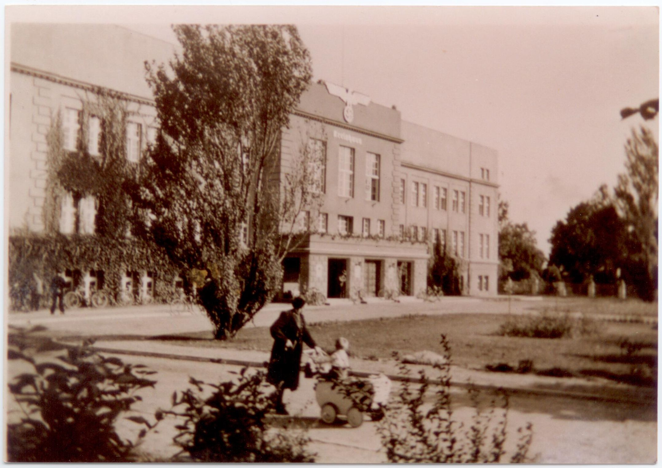 Stare zdjęcie budynku, przed którym stoi kobieta i dziecko.