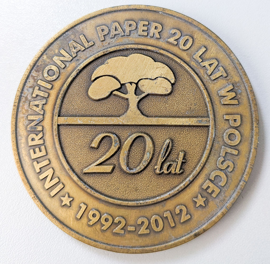 Brązowy medal z grafiką drzewa i napisem „International Paper 20 lat w Polsce 1992-2012.
