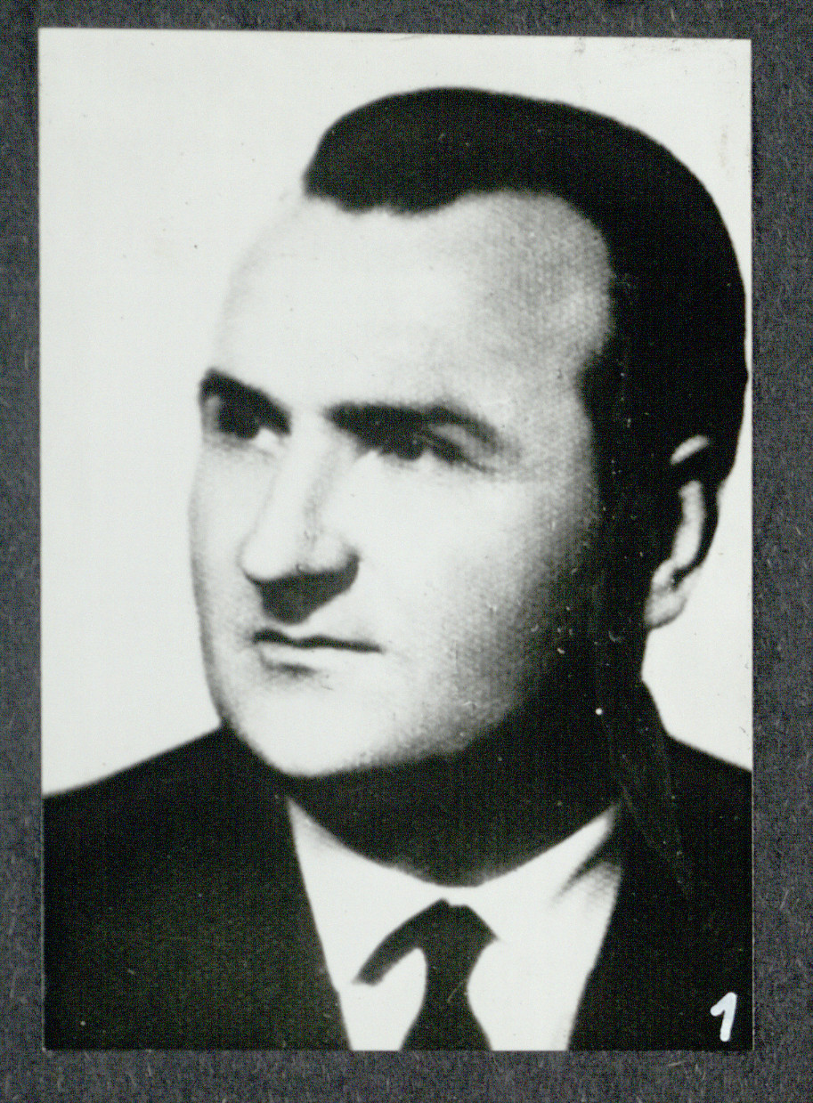 Czarno-biały portret mężczyzny w garniturze i krawacie, zwróconego lekko w prawo.