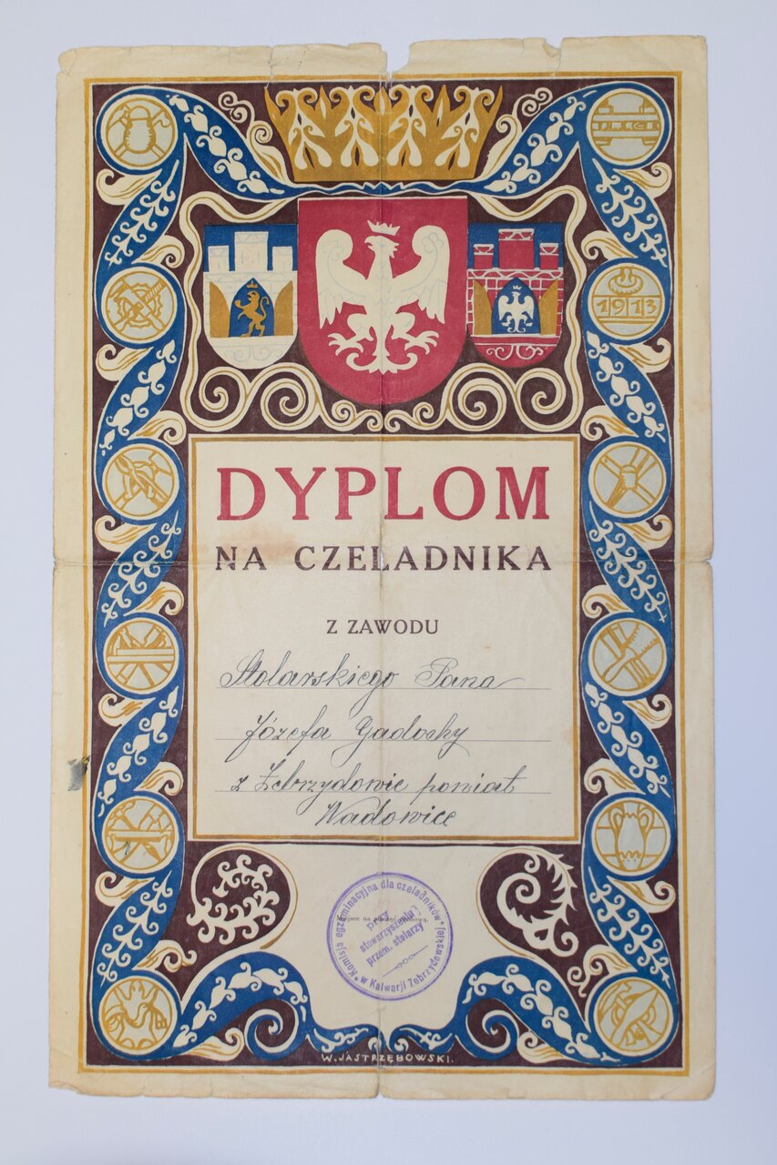Ozdobny certyfikat z ozdobną obwódką, symbolami heraldycznymi i tekstem w języku polskim, zatytułowanym „Dyplom na Czeladnika.