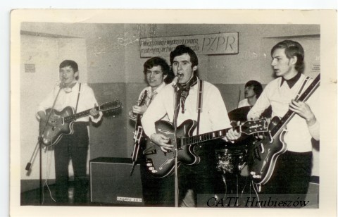 Czarno-białe zdjęcie przedstawiające grupę mężczyzn grających na gitarach.