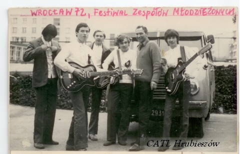 Zdjęcie grupy ludzi z gitarami przed ciężarówką.