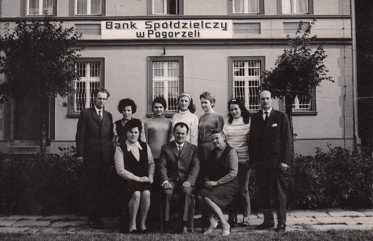 Grupa osób pozujących przed budynkiem.