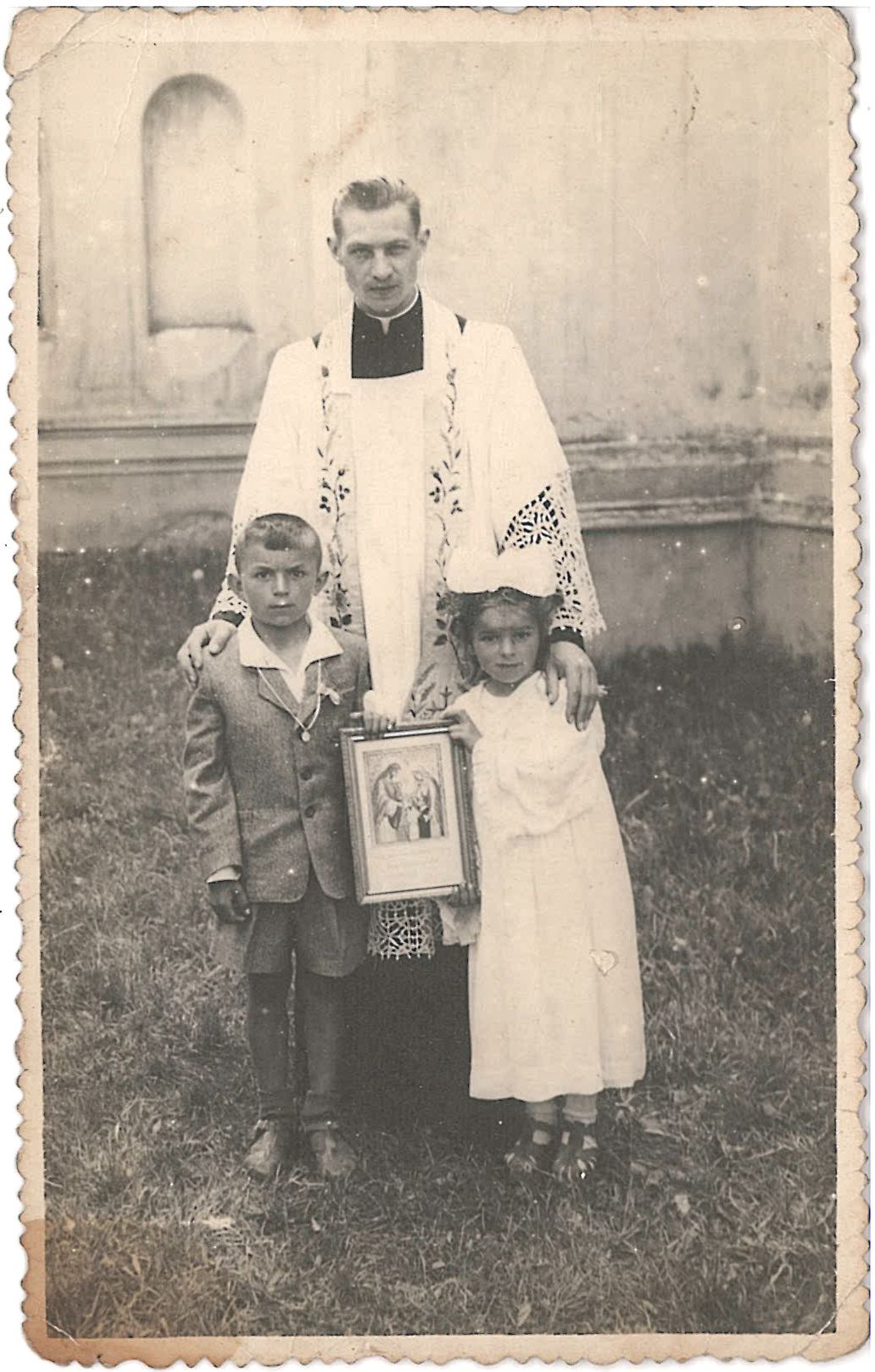 Stare zdjęcie księdza z dwójką dzieci.