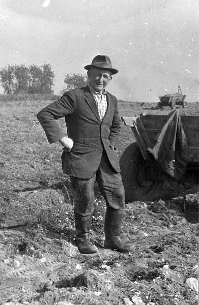 Mężczyzna w kapeluszu stojący obok traktora.