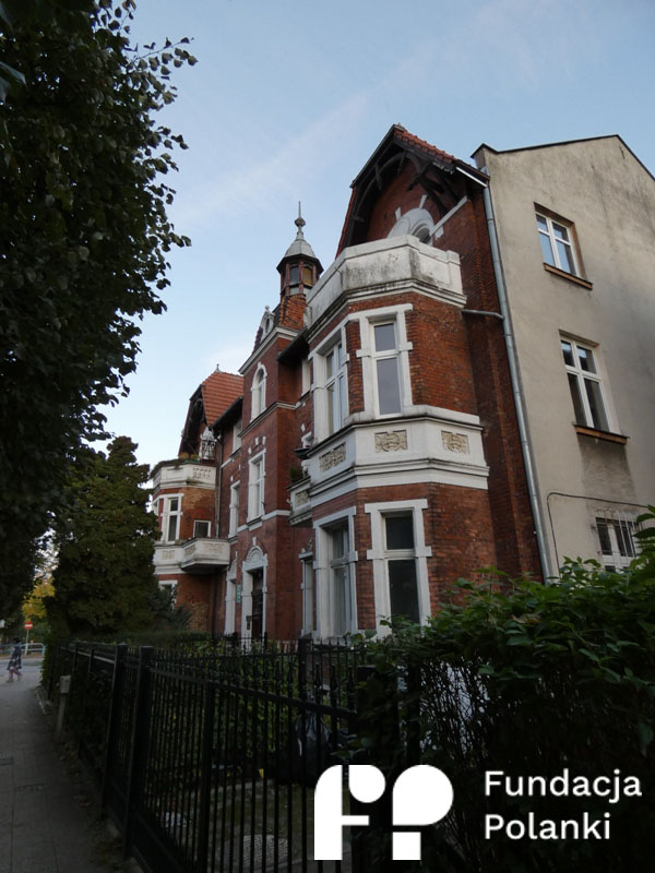 Budynek z czerwonej cegły z płotem przed nim.