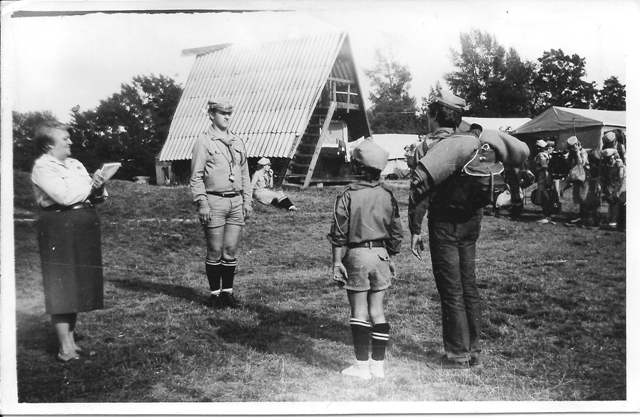 Harcerz stoi przed namiotem.